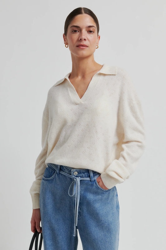 Woman wearing a cream sweater and blue jeans against a white background from Second Female