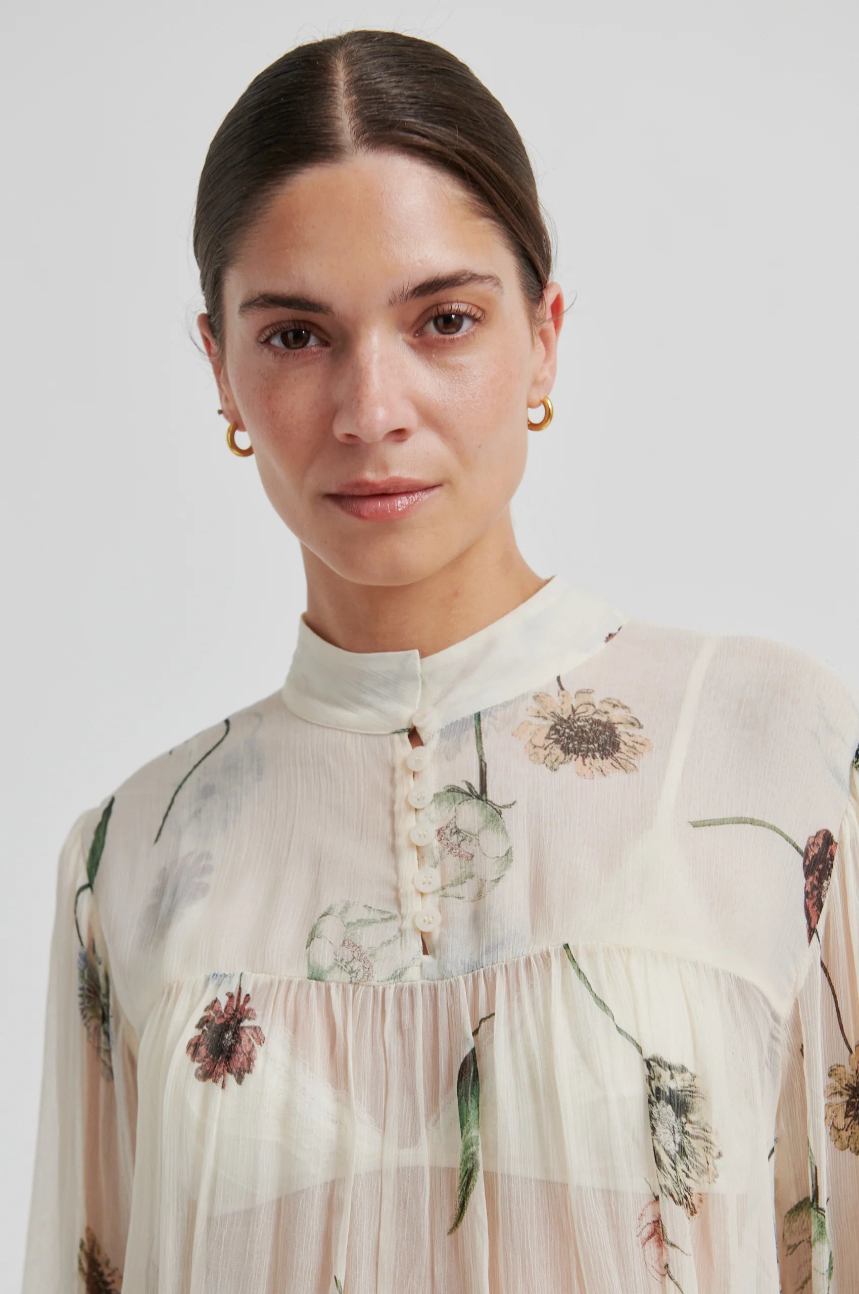 Woman wearing a floral blouse against a plain background from Second Female