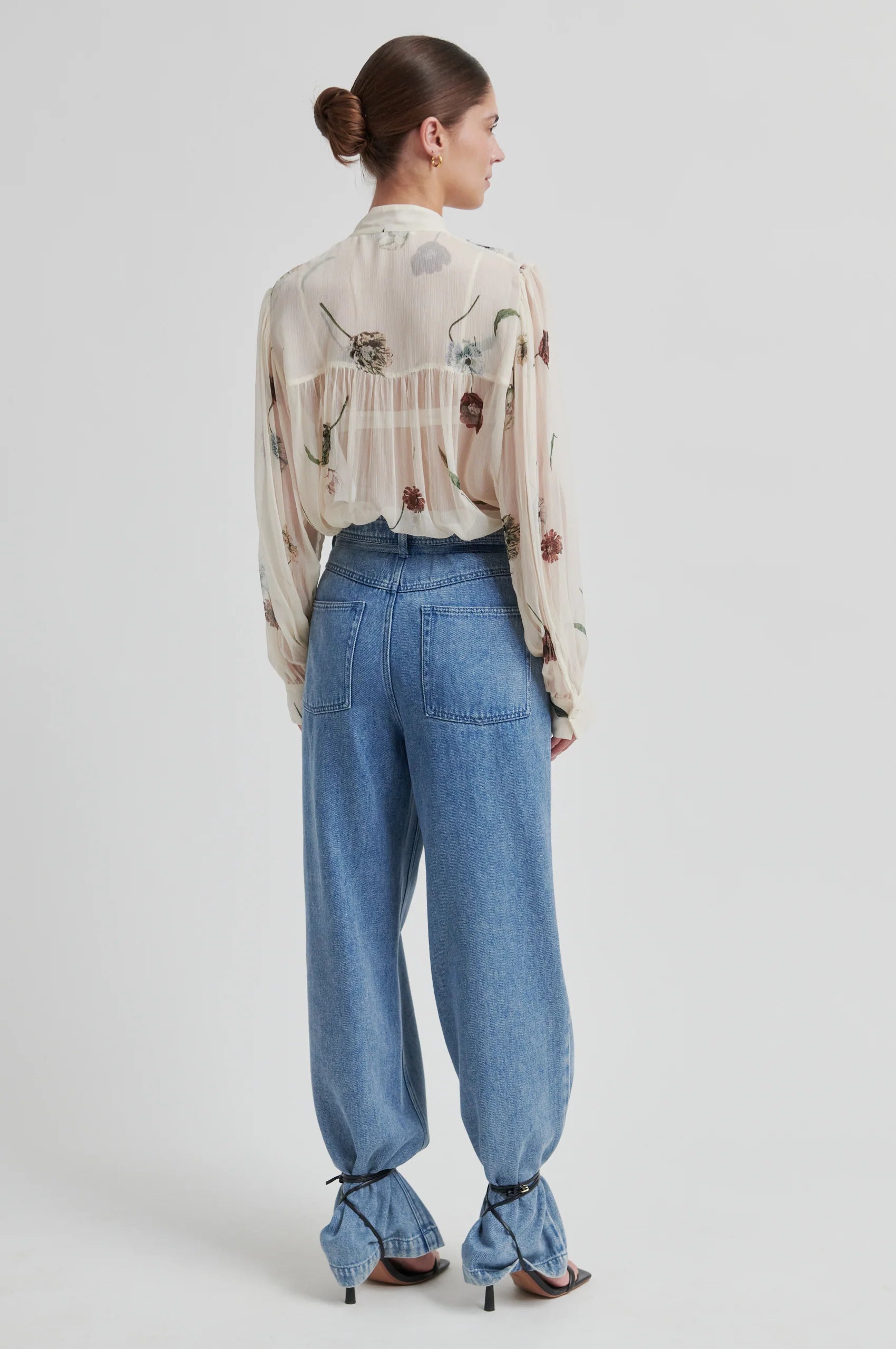 Rear view of Woman wearing a patterned blouse and blue jeans on a white background