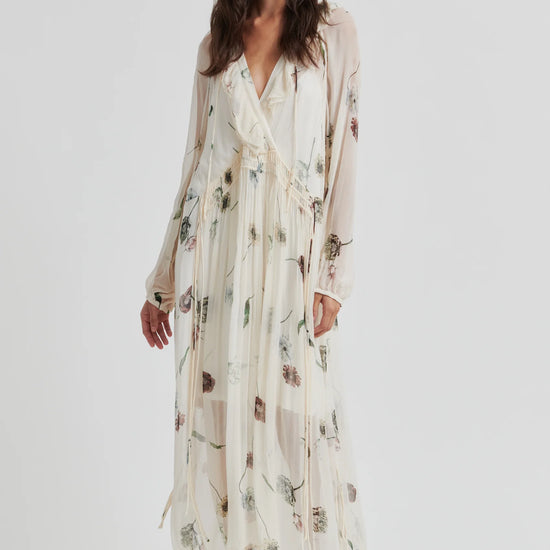 Woman wearing a long, light-colored dress with floral patterns on a white background from Second Female