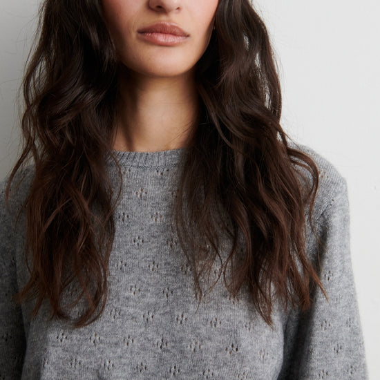 Woman wearing a gray sweater against a plain background from Second Female 