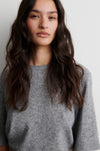 Woman wearing a gray sweater against a plain background from Second Female 