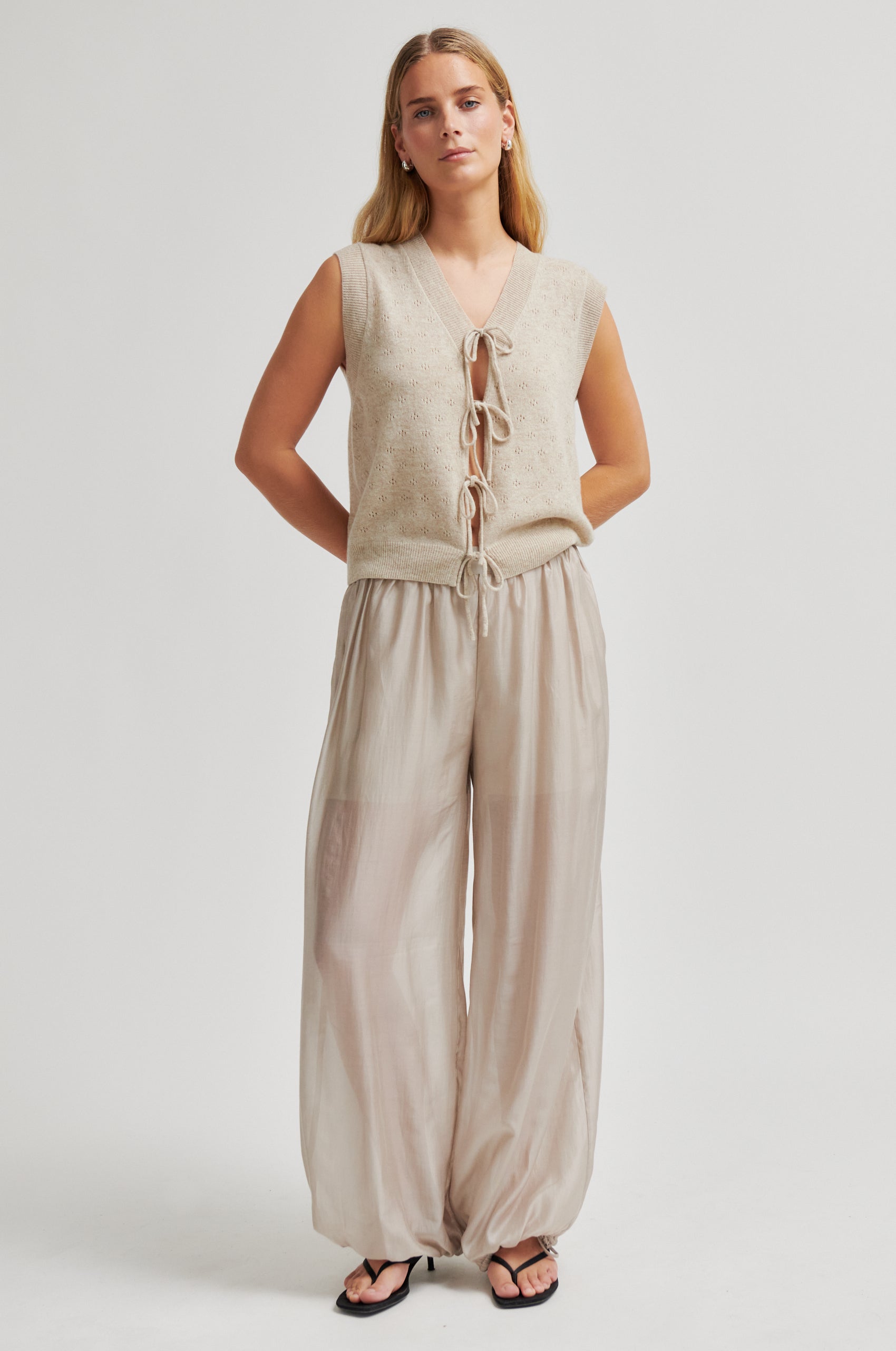 Woman wearing a beige sleeveless top and wide-leg pants on a white background from Second Female
