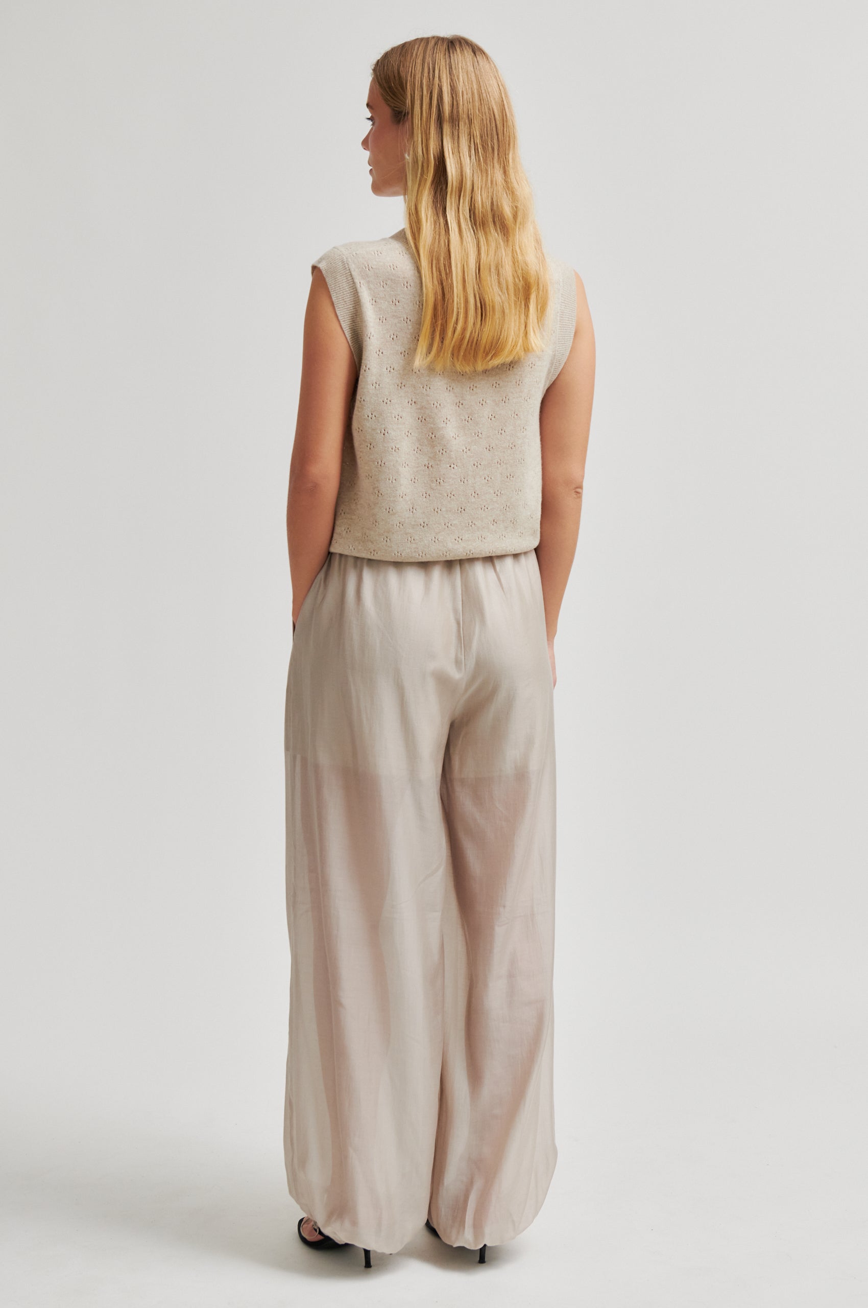 Rear view of Woman wearing a beige sleeveless top and wide-leg pants on a white background from Second Female