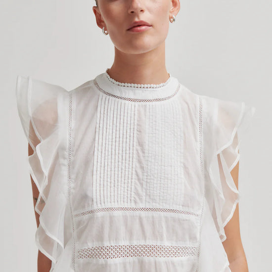 model wearing white frill top on plain background