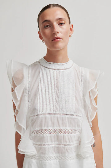 model wearing white frill top on plain background