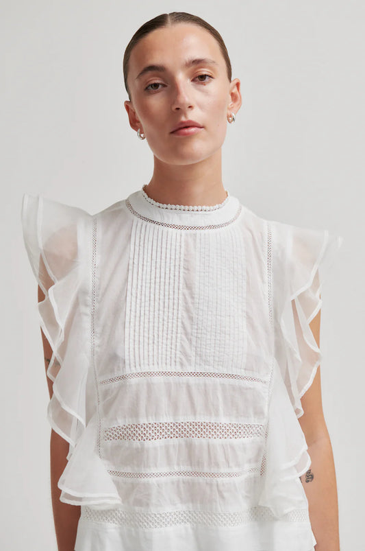 model wearing white frill top on plain background
