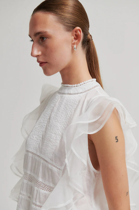 women facing the left wearing a white frill top 