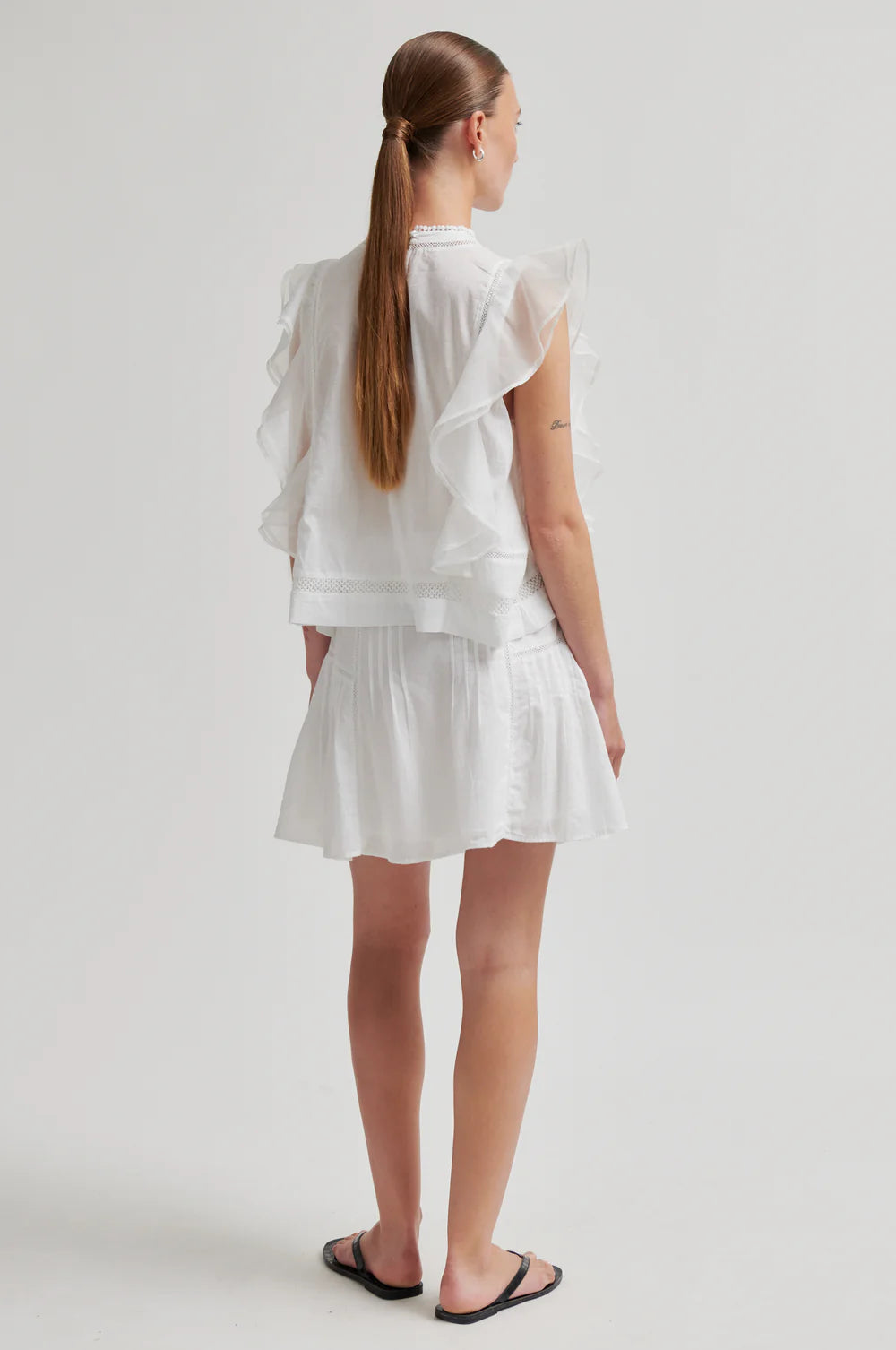 Woman wearing a white outfit on a plain background