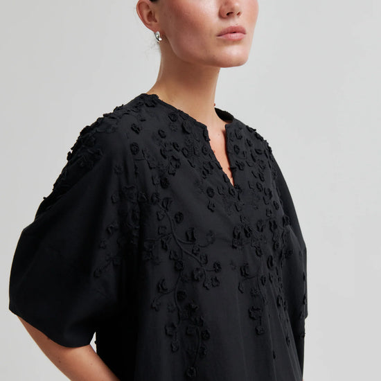 Black dress with applique flowers on a model close up