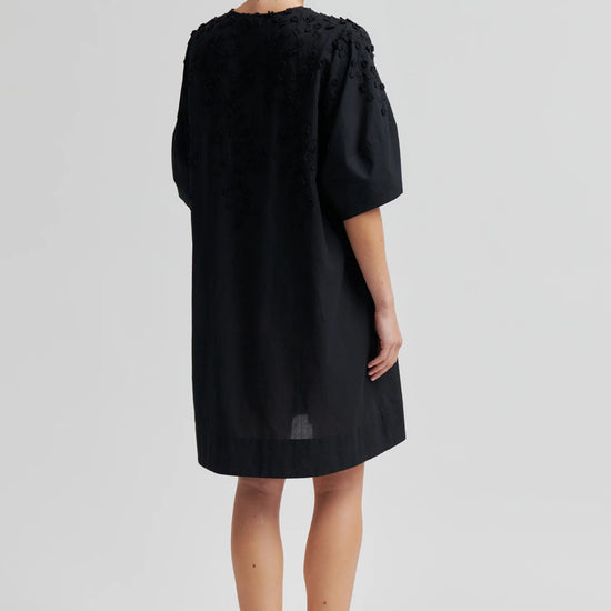 Black dress with applique flowers on a model rear view