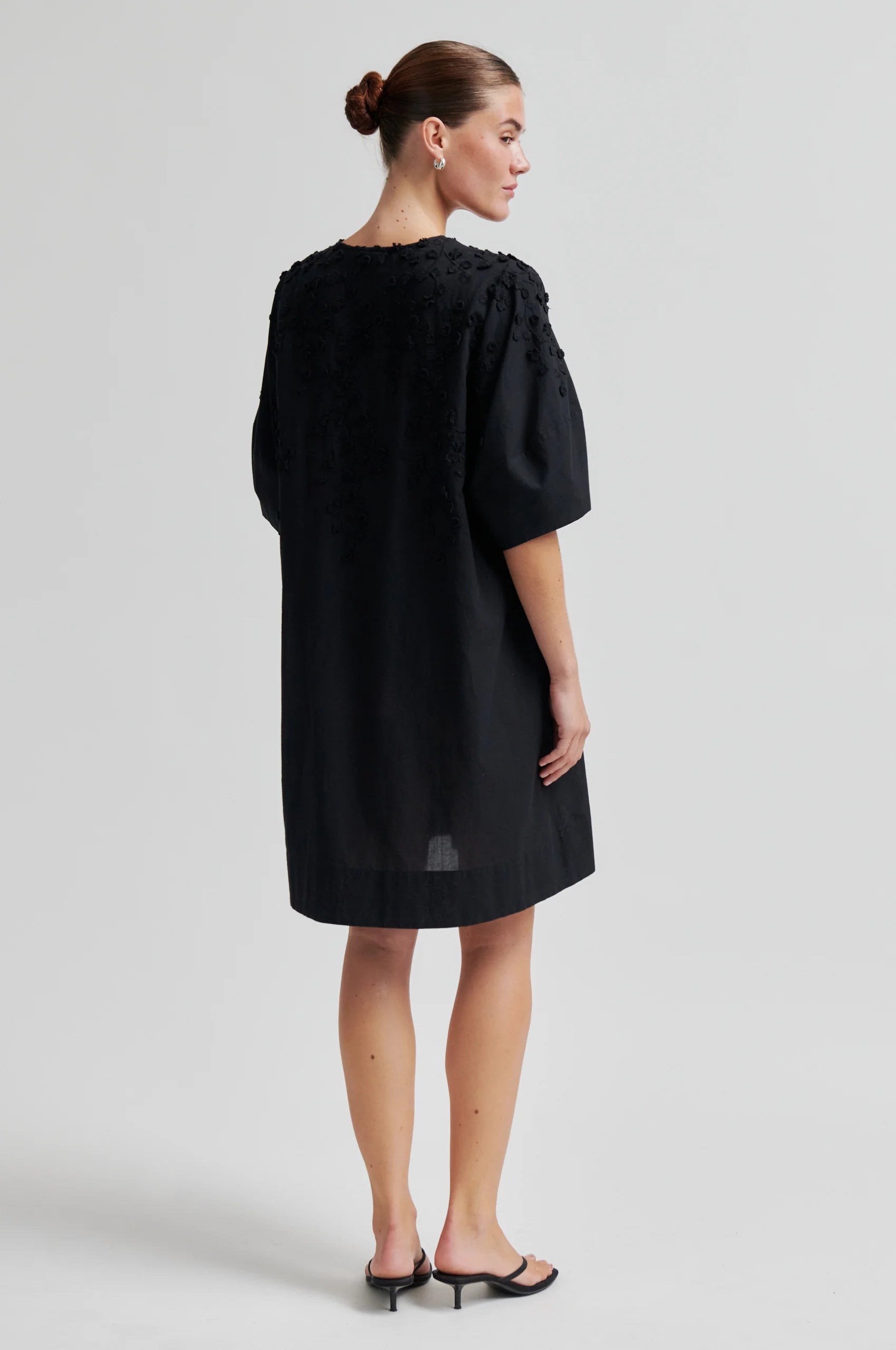 Black dress with applique flowers on a model rear view