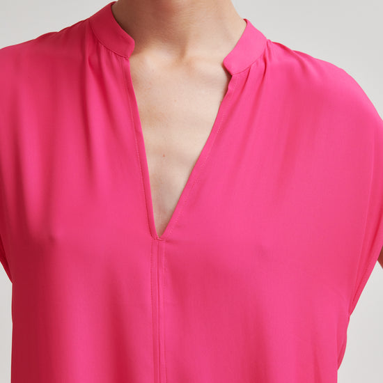 Close-up of a bright pink sleeveless top on a neutral background