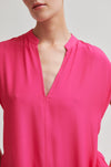Close-up of a bright pink sleeveless top on a neutral background