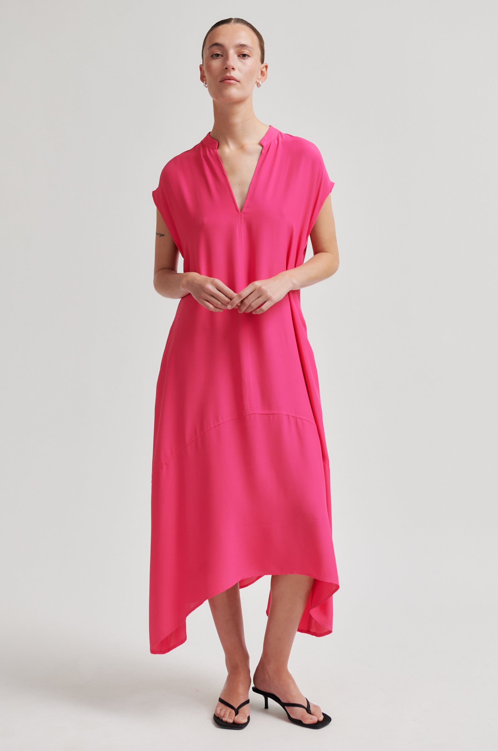 Woman wearing a bright pink dress on a plain background from Second Female