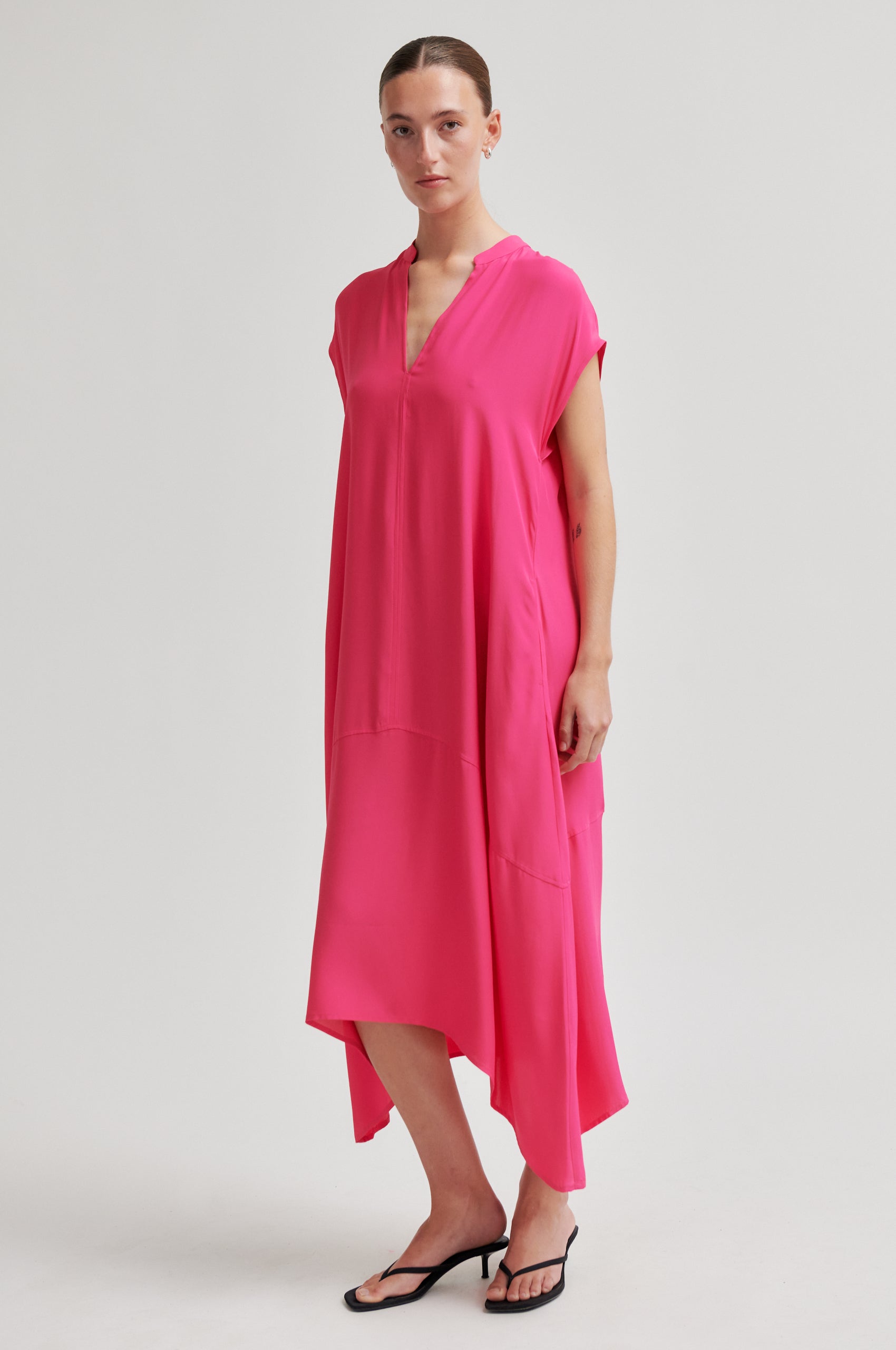 Woman wearing a bright pink dress on a white background