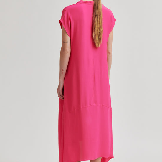 Woman wearing a bright pink dress on a white background