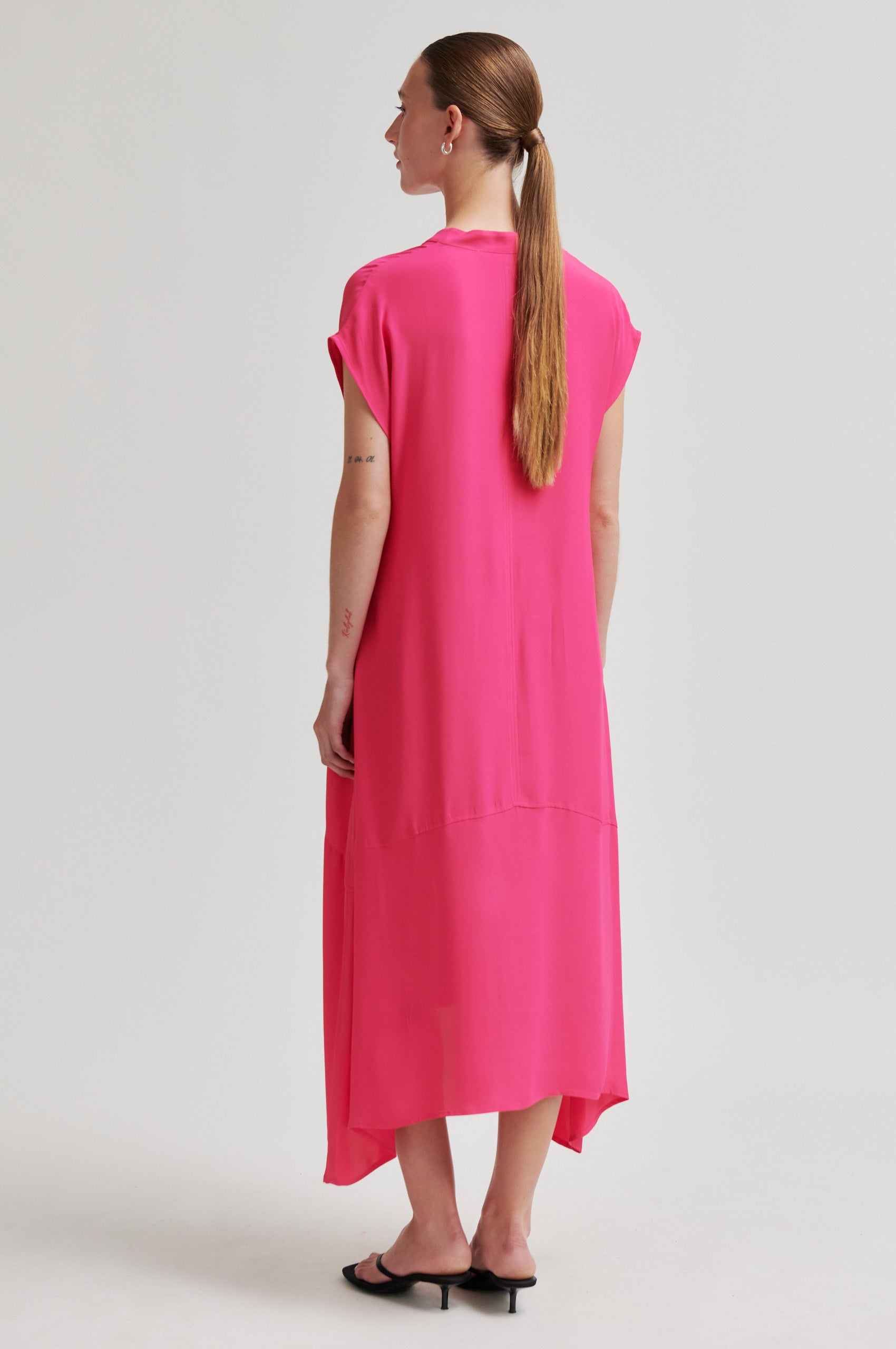 Woman wearing a bright pink dress on a white background