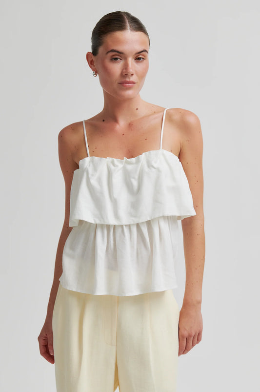 Woman wearing a white layered top and light yellow pants on a plain background from Second Female