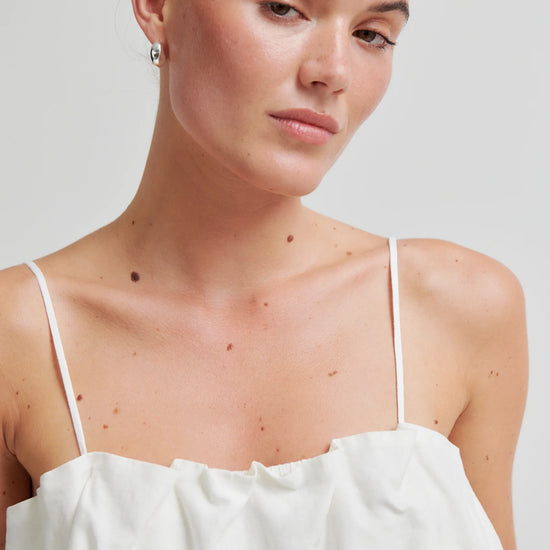 Woman wearing a white top against a plain background from Second Female
