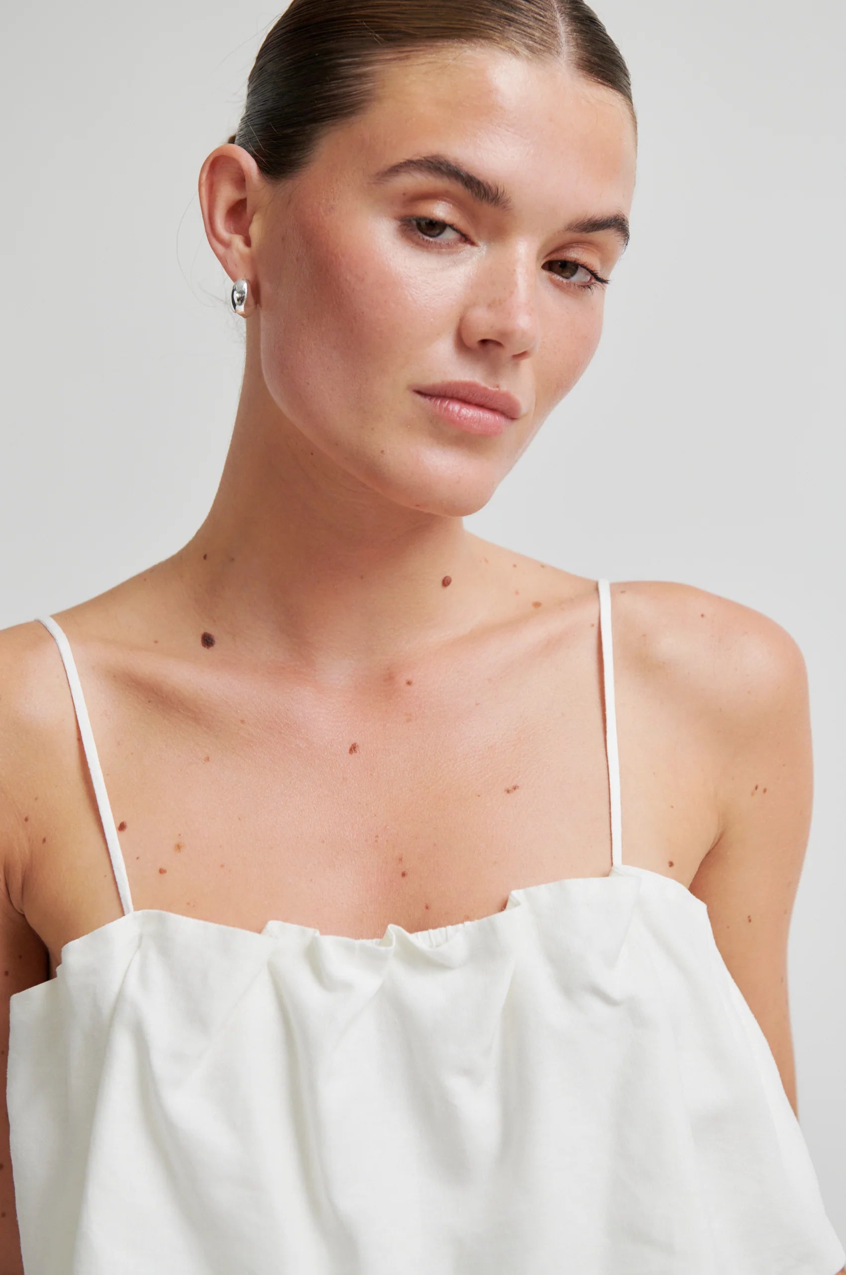 Woman wearing a white top against a plain background from Second Female