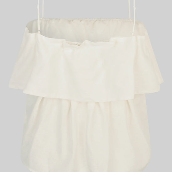 Cream-colored top with ruffled layers on a light gray background rear view