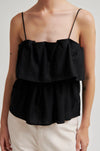 Black ruffled top worn by a person on a plain background from second female