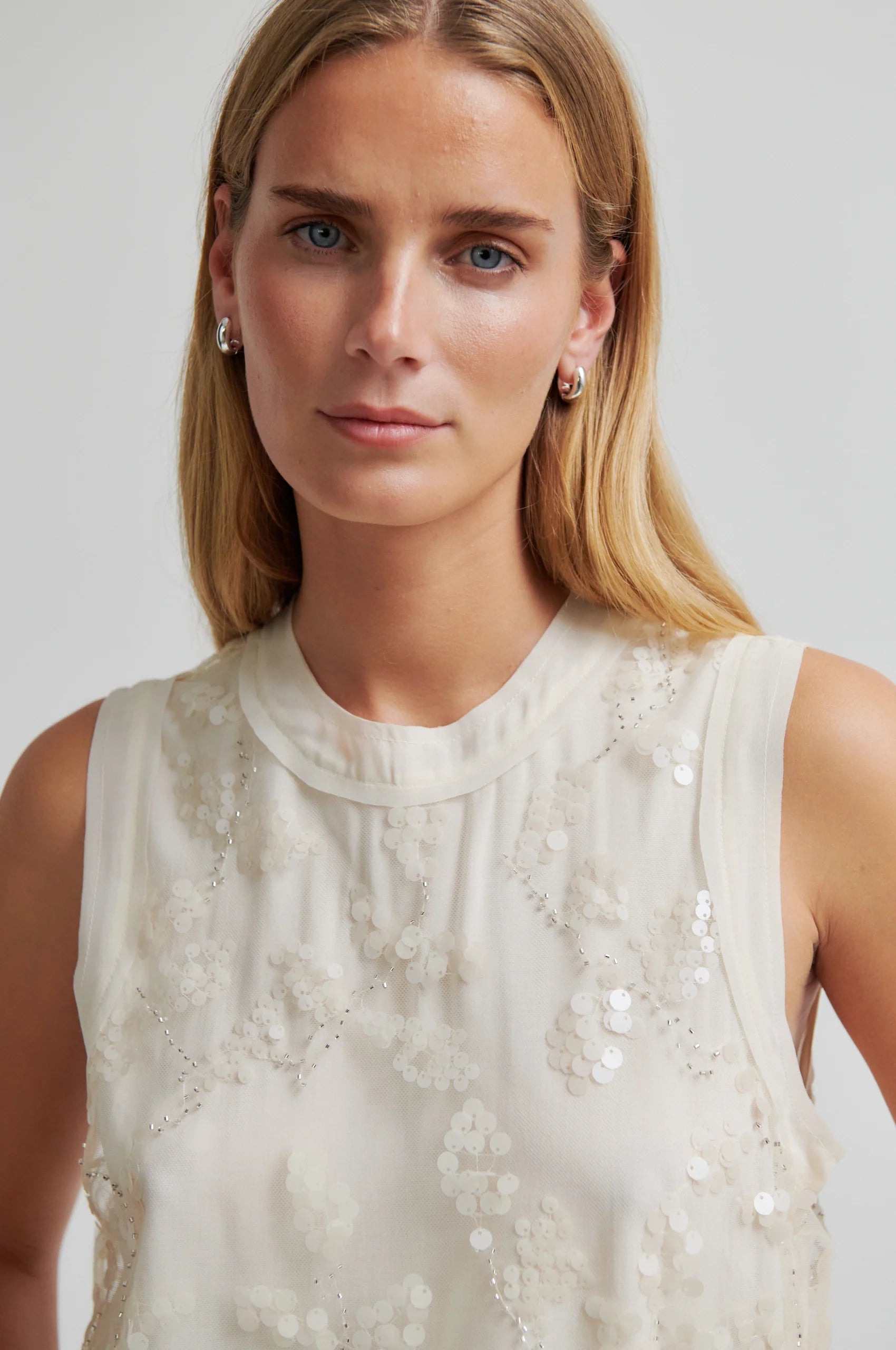 Woman wearing a white sleeveless top with lace details against a plain background from Second Female