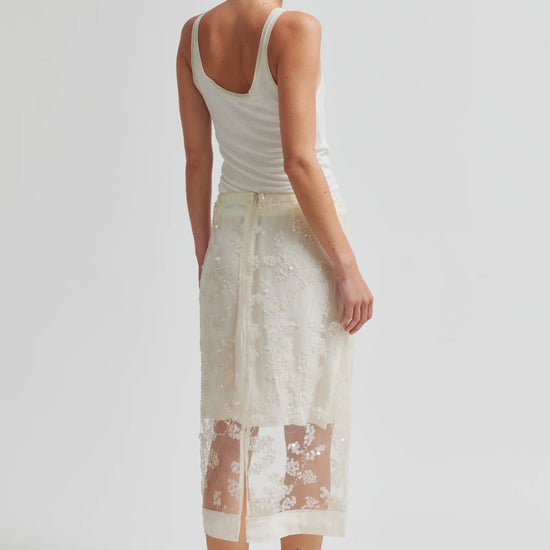 Woman wearing a white lace skirt and white tank top on a plain background from Second Female