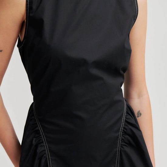 close up of model wearing black dress on white background