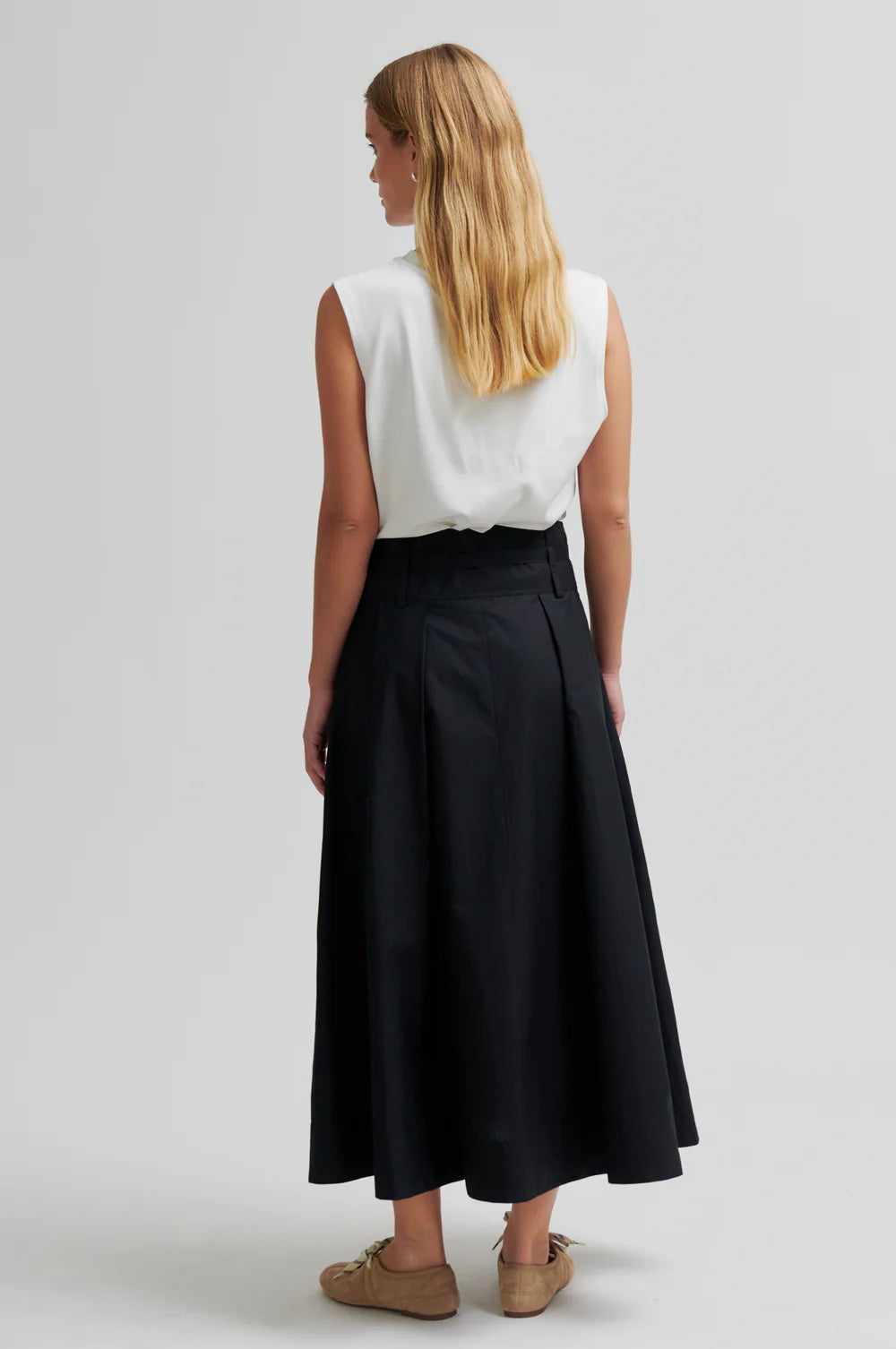 model wearing black skirt and white top facing away from camera