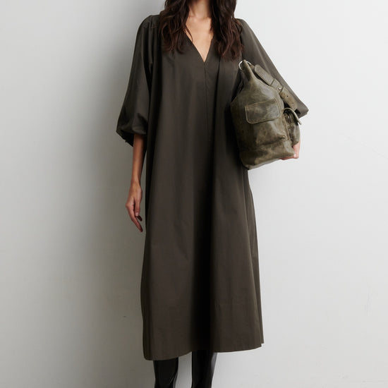 Woman wearing a long olive green dress holding a matching bag against a white background from Second Female