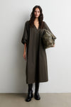 Woman wearing a long olive green dress holding a matching bag against a white background from Second Female