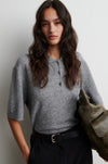 Woman wearing a gray cashmere blend sweater holding a green bag against a plain background from Second Female