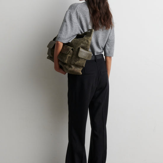 Person holding a green bag against a white background from second female