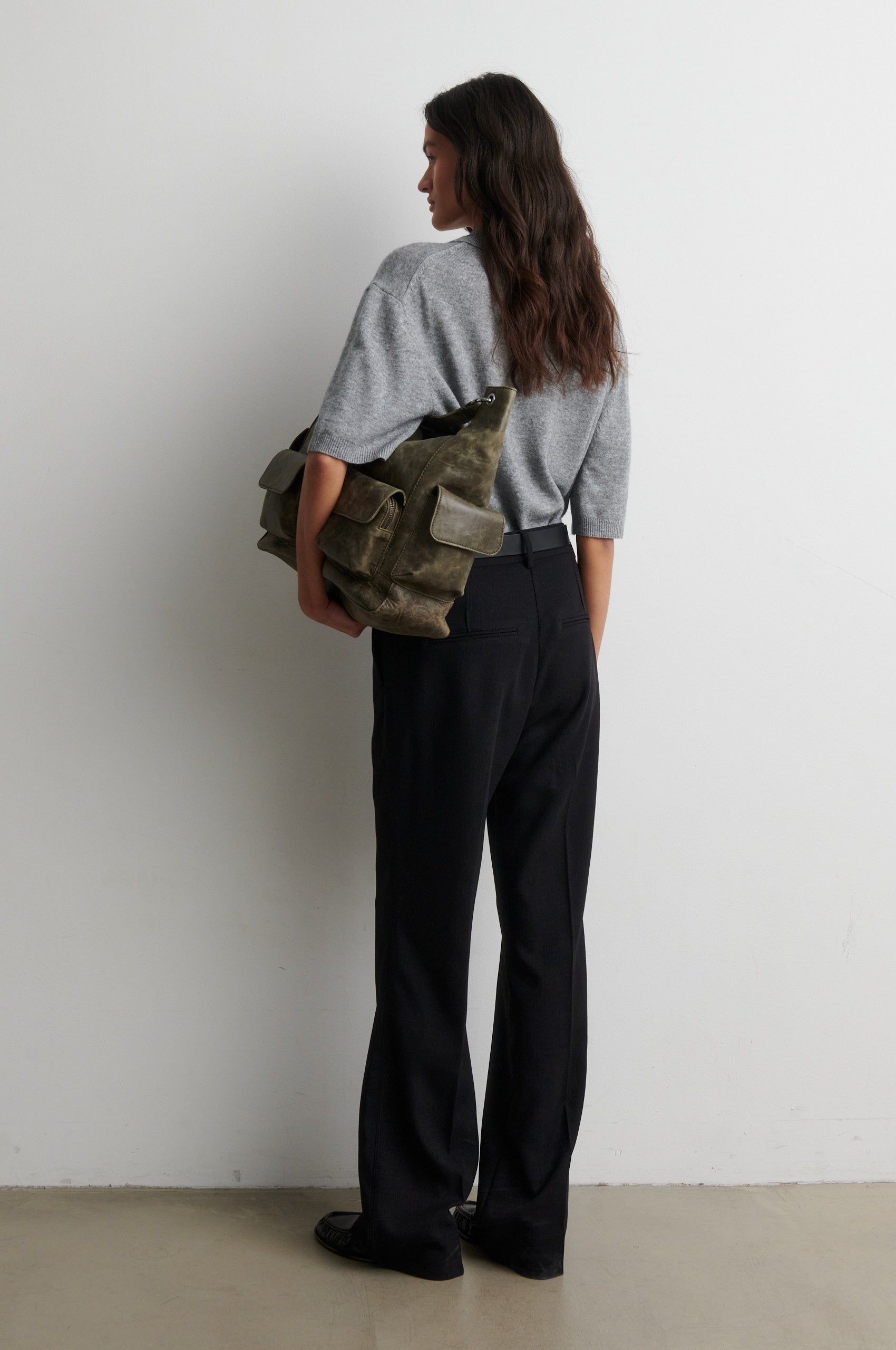 Person holding a green bag against a white background from second female