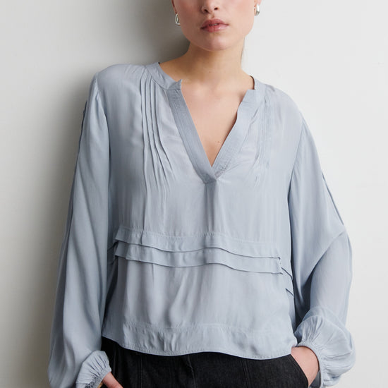 Woman wearing a light blue blouse against a plain background from Second Female