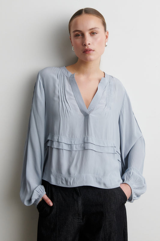 Woman wearing a light blue blouse against a plain background from Second Female