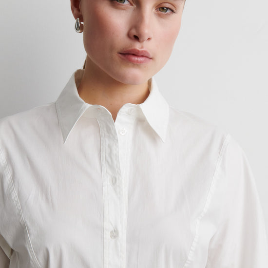 Woman wearing a white shirt against a plain background from Second Female