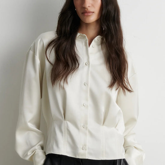model wearing a cream satin button up shirt with black trousers on a plain white background