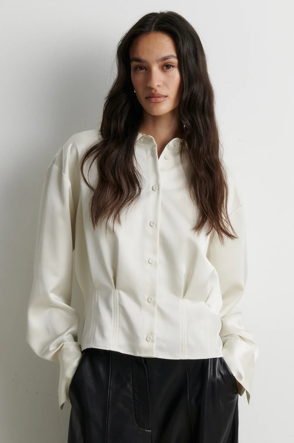 model wearing a cream satin button up shirt with black trousers on a plain white background