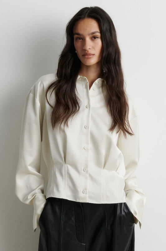 model wearing a cream satin button up shirt with black trousers on a plain white background