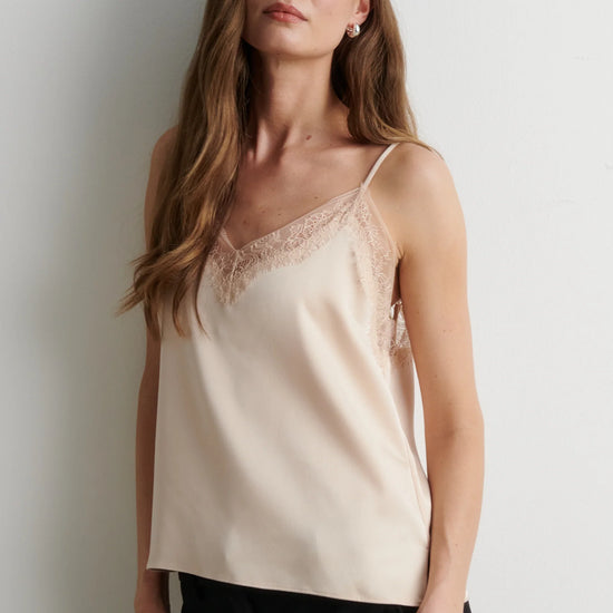 woman wearing pale pink camisole top with black trousers