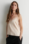 woman wearing pale pink camisole top with black trousers