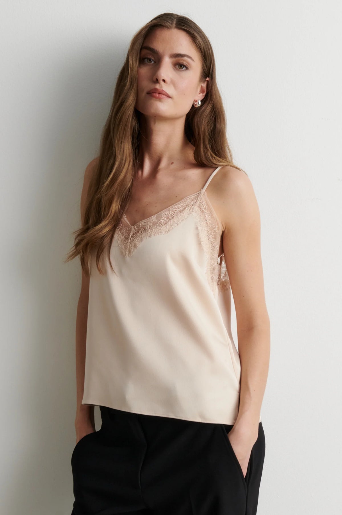 woman wearing pale pink camisole top with black trousers