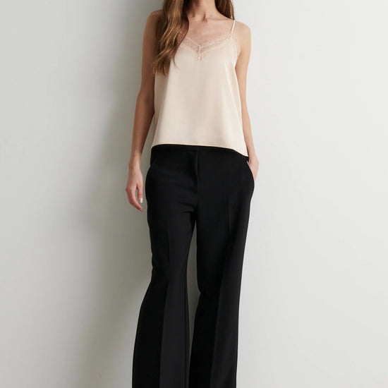 Woman wearing pale pink lace trim camisole with black trousers