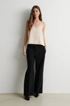 Woman wearing pale pink lace trim camisole with black trousers