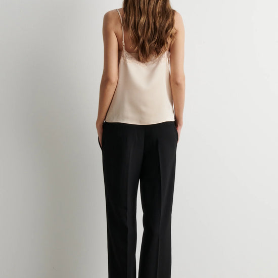 Rear view of woman wearing pale pink camisole top with black trousers