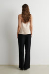 Rear view of woman wearing pale pink camisole top with black trousers