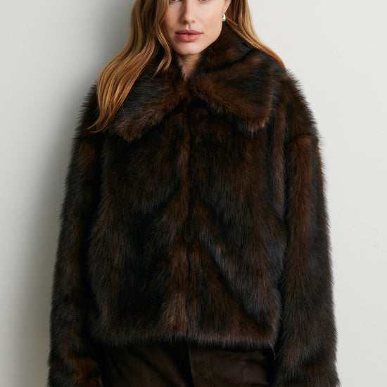 Woman wearing a dark brown fur coat against a plain background from Second Female